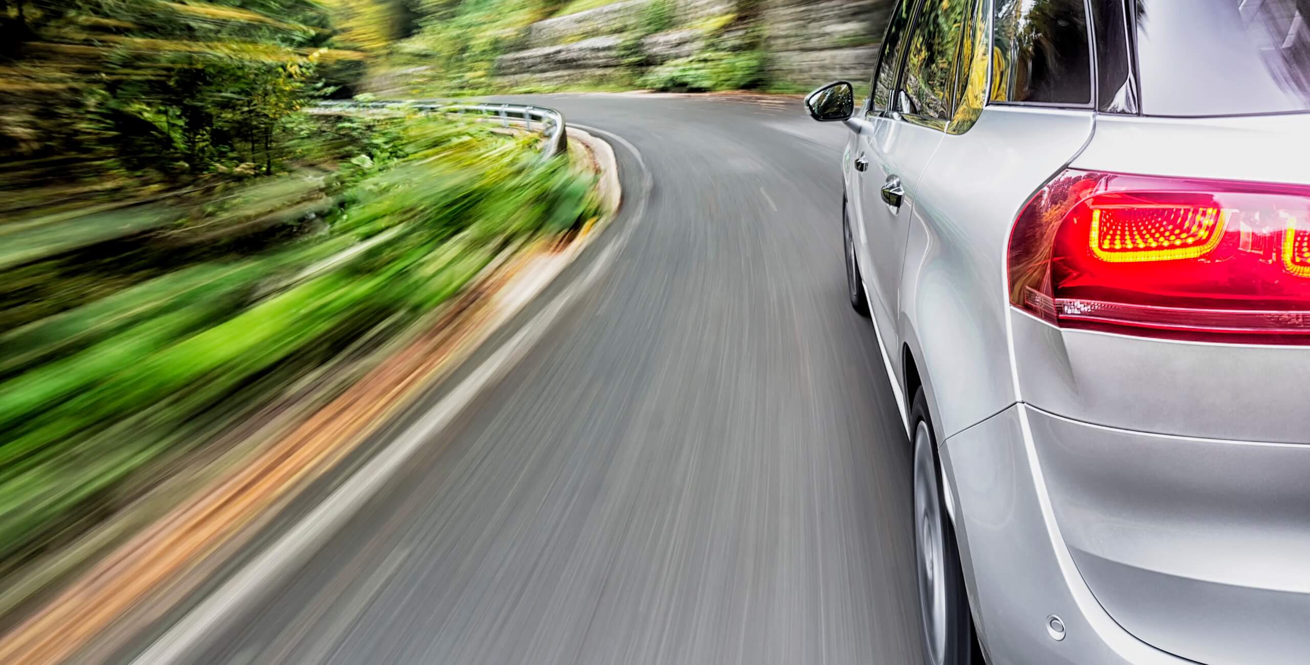 side view of a car driving on a curved road